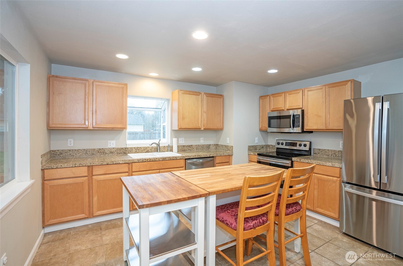407 18th Street Southwest Puyallup, WA 98371 - Photo 11 of 40 a kitchen with stainless steel appliances granite countertop a stove a sink a microwave a refrigerator with white cabinets and wooden floor
