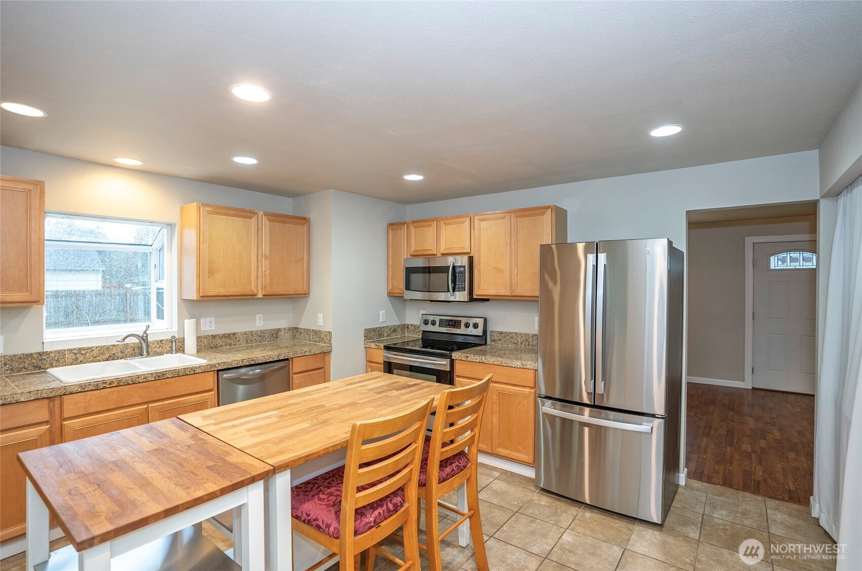 407 18th Street Southwest Puyallup, WA 98371 - Photo 8 of 40 a kitchen with stainless steel appliances granite countertop a refrigerator a stove a sink a dining table and chairs