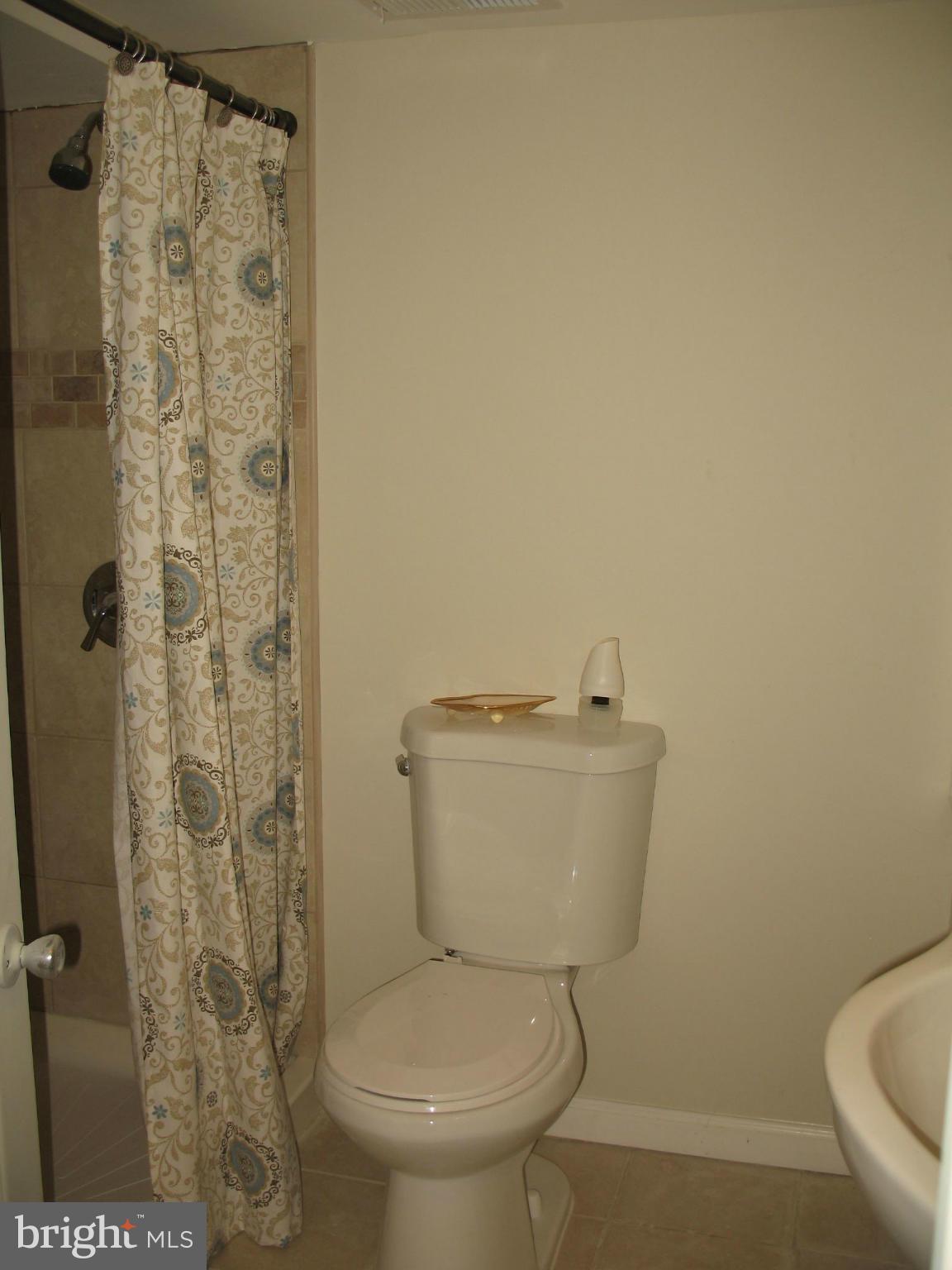 1213 West Old Cold Spring Lane Baltimore, MD 21211 - Photo 13 of 15 a white toilet sitting next to a shower curtain