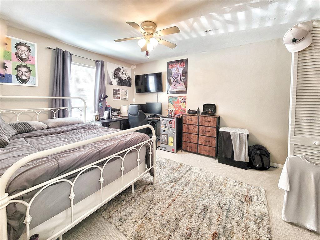 2360 Southwest Archer Road, Unit 801 Gainesville, FL 32608 - Photo 17 of 27 a bedroom with furniture and a flat screen tv