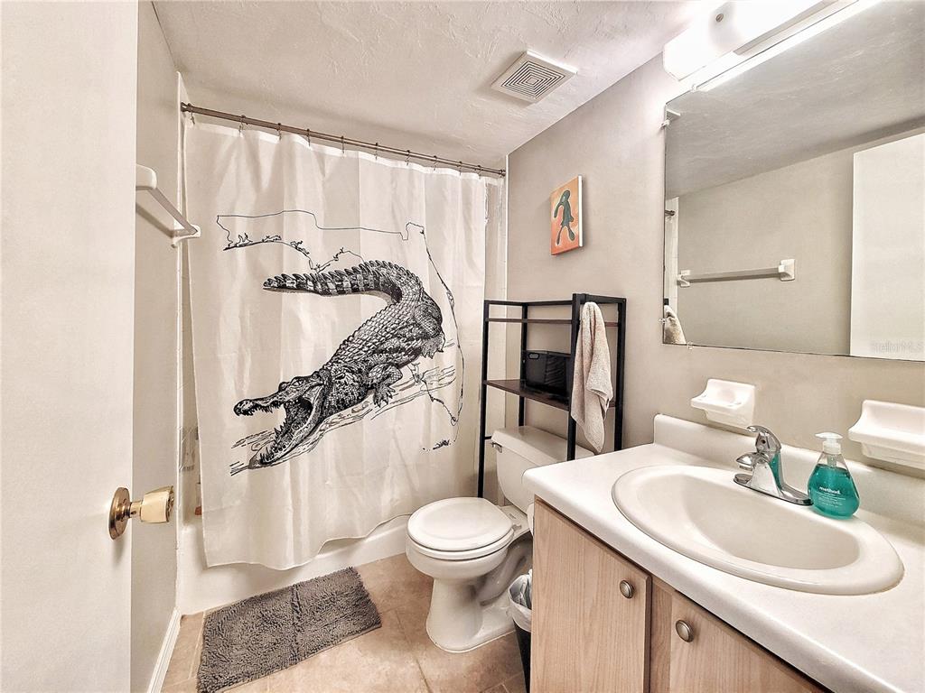 2360 Southwest Archer Road, Unit 801 Gainesville, FL 32608 - Photo 23 of 27 a bathroom with a toilet sink a mirror a shower and vanity