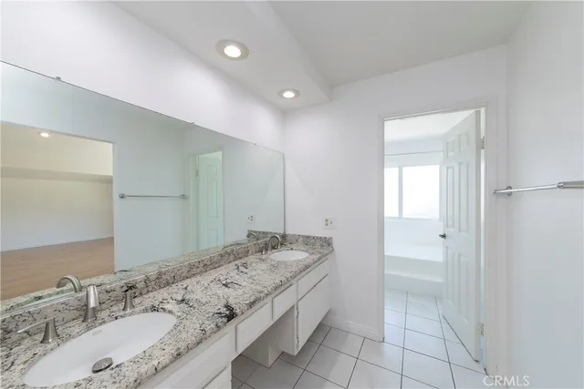 a spacious bathroom with a granite countertop sink and a mirror