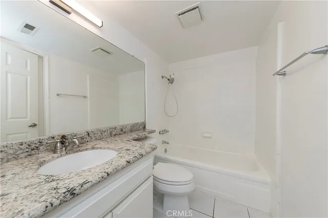 a bathroom with a granite countertop sink a toilet and shower