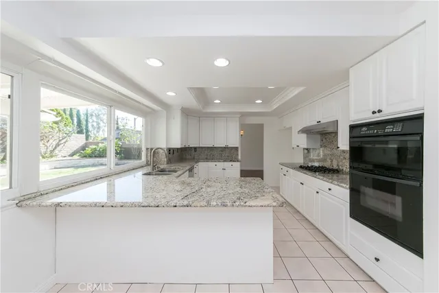 a large kitchen with kitchen island granite countertop a large window and a counter top space
