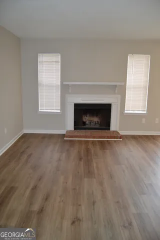an empty room with wooden floor fireplace and windows