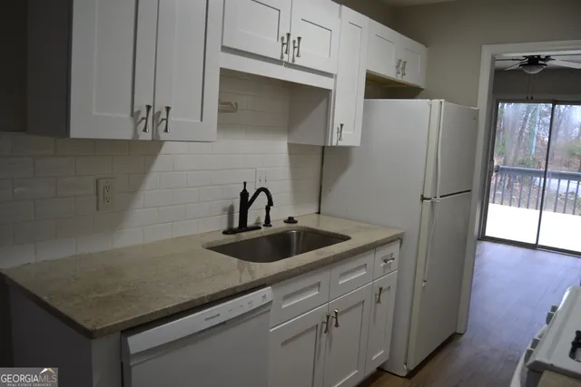 a kitchen with stainless steel appliances granite countertop a refrigerator a sink and white cabinets