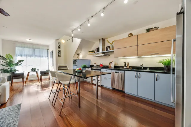 a kitchen with stainless steel appliances granite countertop wooden floors a stove and white cabinets