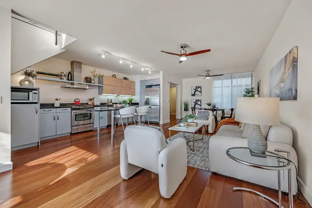 a living room with furniture kitchen view and a wooden floor
