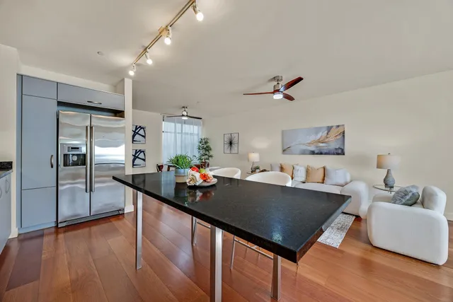 a living room with stainless steel appliances furniture a rug kitchen view and a chandelier