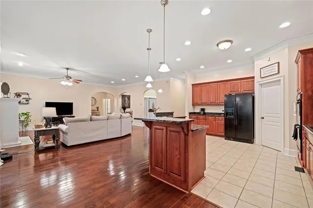 a living room with stainless steel appliances kitchen island granite countertop a large kitchen island a stove a refrigerator a sink and a dining table with wooden floor