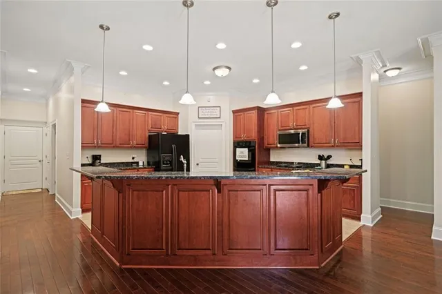 a kitchen with stainless steel appliances kitchen island granite countertop wooden cabinets and sink