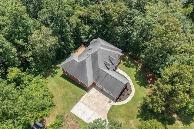 an aerial view of a house with outdoor space and trees all around