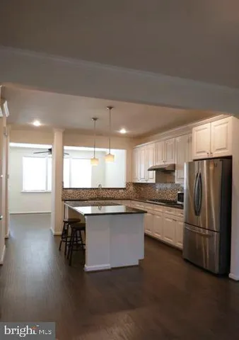 a kitchen with stainless steel appliances a stove a sink dishwasher a refrigerator and a dining table with wooden floor