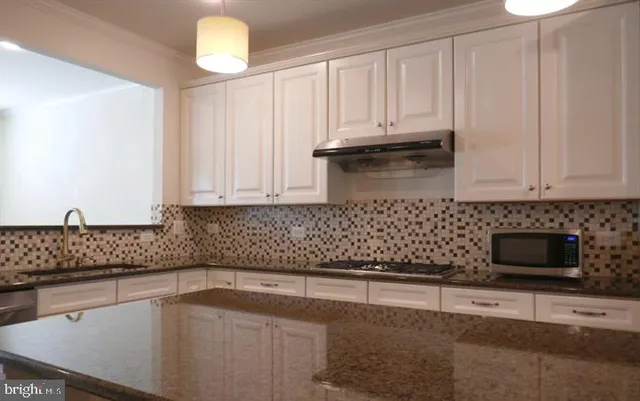 a kitchen with granite countertop white cabinets and stainless steel appliances