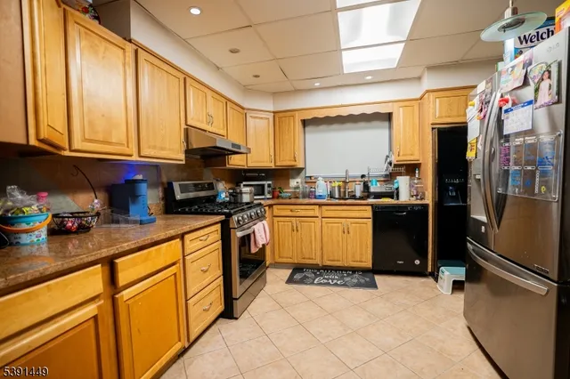 a kitchen with stainless steel appliances granite countertop a refrigerator a stove top oven a sink and dishwasher