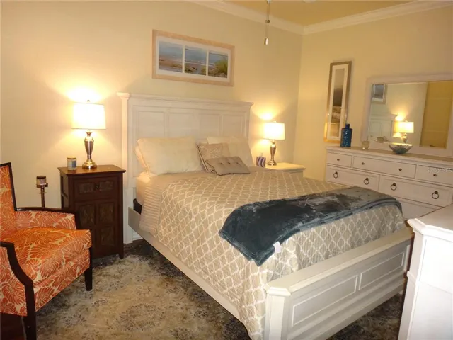 a spacious bedroom with a bed and dresser with lamp