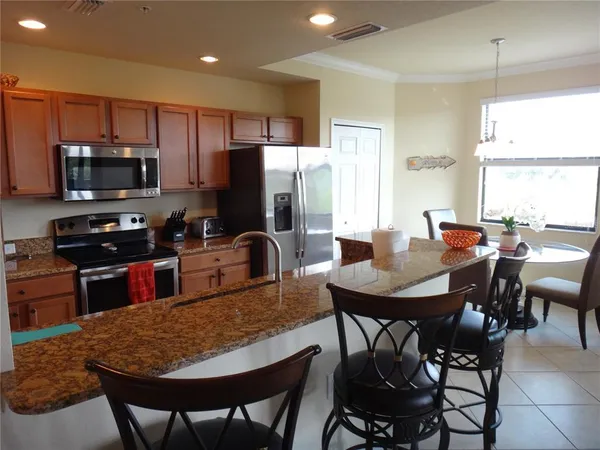 a kitchen with stainless steel appliances granite countertop a refrigerator a stove a sink a dining table and chairs