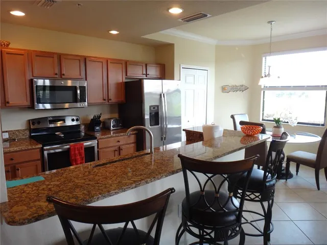 a kitchen with stainless steel appliances granite countertop a refrigerator a stove a sink a dining table and chairs