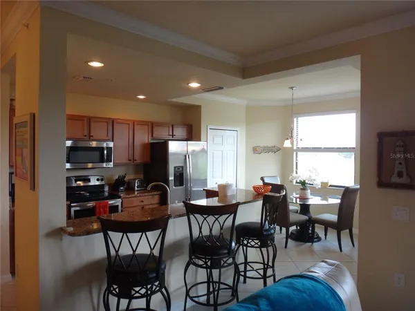a dining room with stainless steel appliances kitchen island granite countertop a dining table chairs and a refrigerator