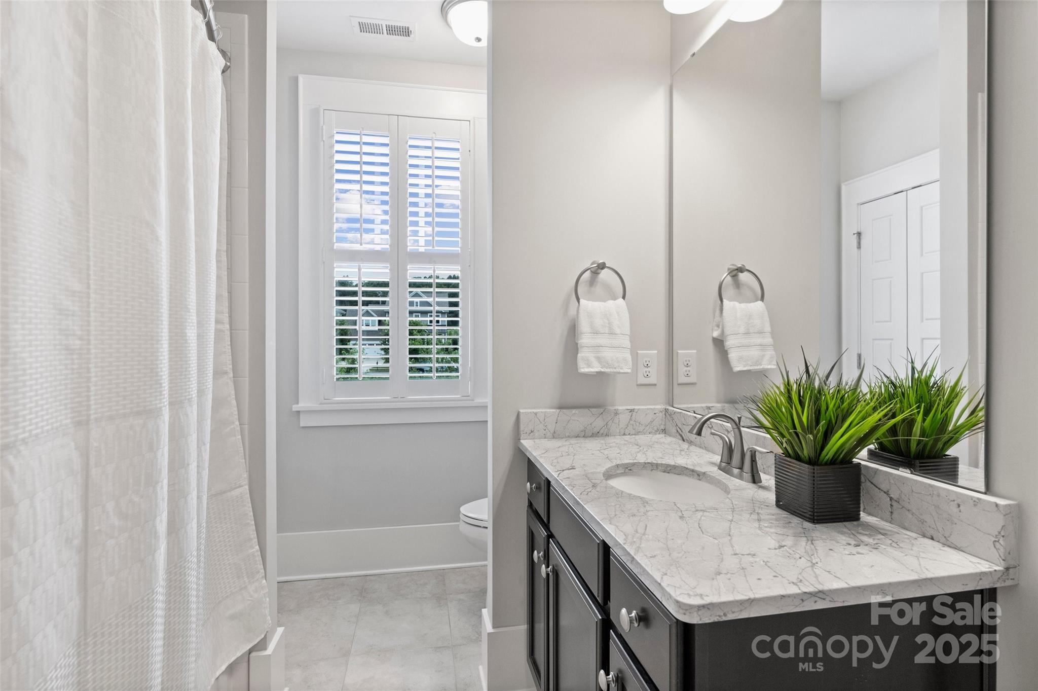 1550 Matthew McClure Circle Davidson, NC 28036 - Photo 27 of 38 a bathroom with a granite countertop sink a potted plant and a window