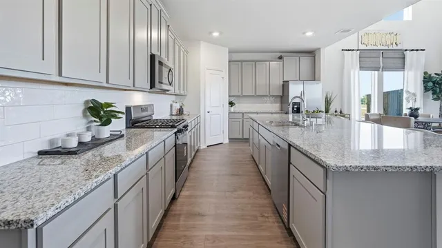 a kitchen with stainless steel appliances granite countertop a sink a stove top oven a counter space and cabinets