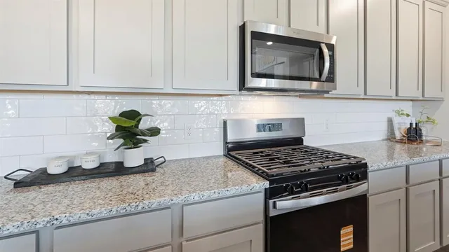 a kitchen with granite countertop a stove a sink and cabinets