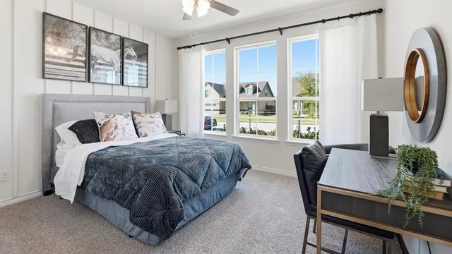 a bedroom with a bed table chair and a window