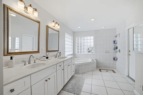 a spacious bathroom with a double vanity sink a large mirror and a bathtub