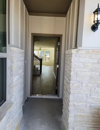 a view of a hallway with wooden floor and a bathroom