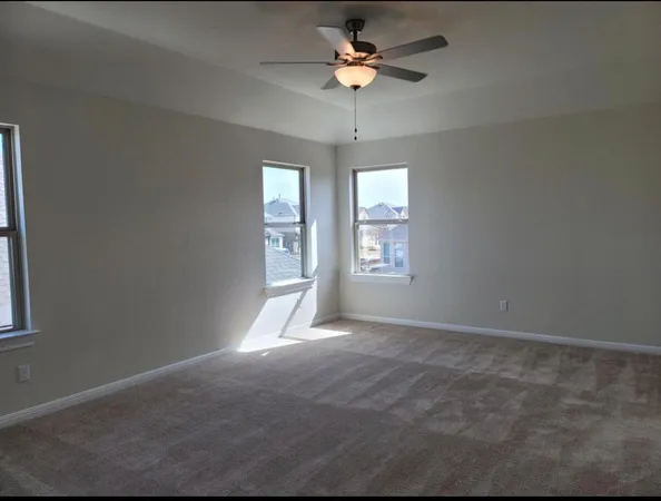 en empty room with windows and ceiling fan