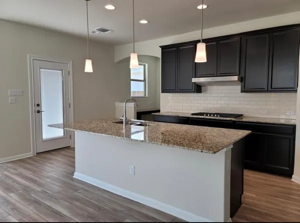 a large kitchen with granite countertop a sink and a refrigerator