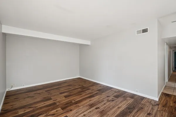 a view of empty room with wooden floor and ceiling fan