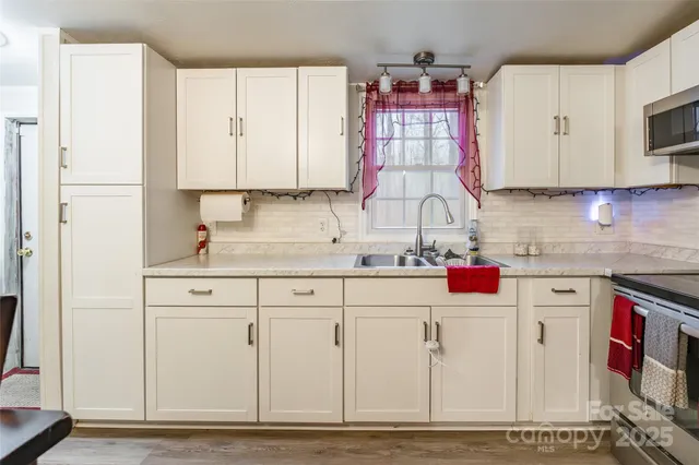 a kitchen with granite countertop a sink cabinets and stainless steel appliances