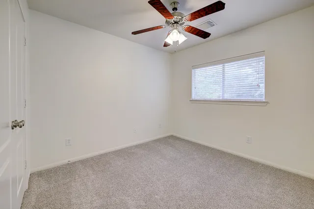 an empty room with a window and a fan