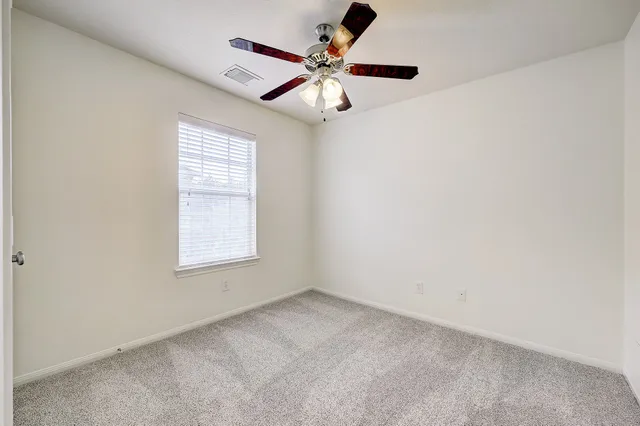 an empty room with a window and a fan