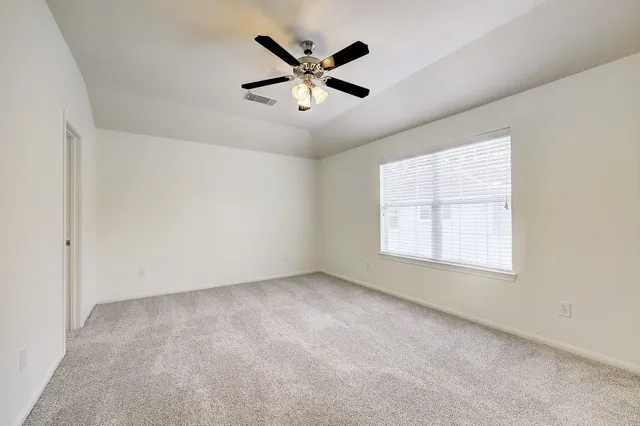 an empty room with ceiling fan and windows