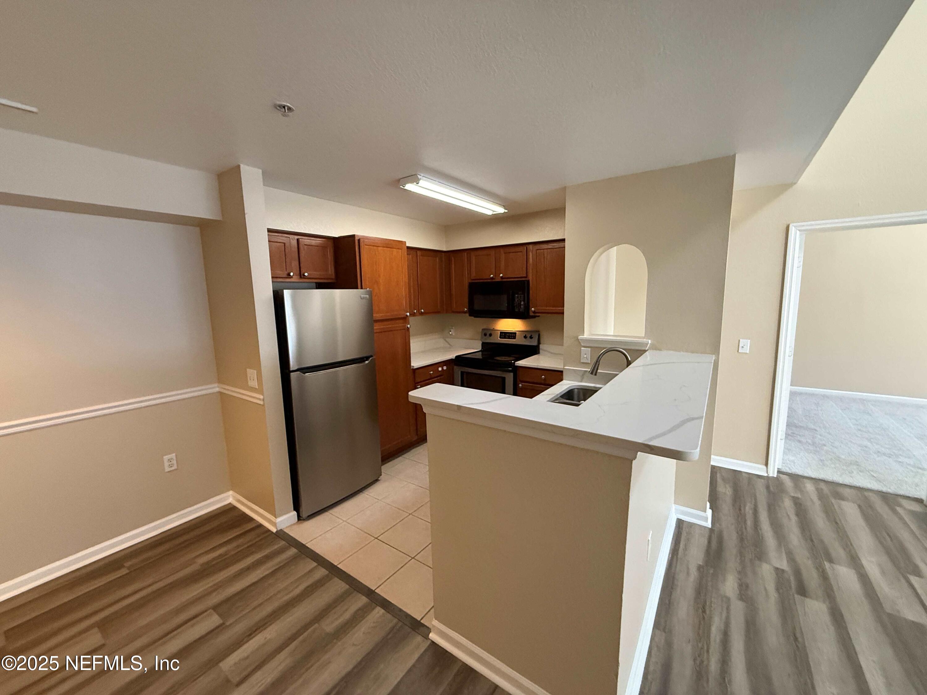 8550 Touchton Road, Unit 1633 Jacksonville, FL 32216 - Photo 13 of 21 a kitchen with a refrigerator a stove top oven and wooden floor