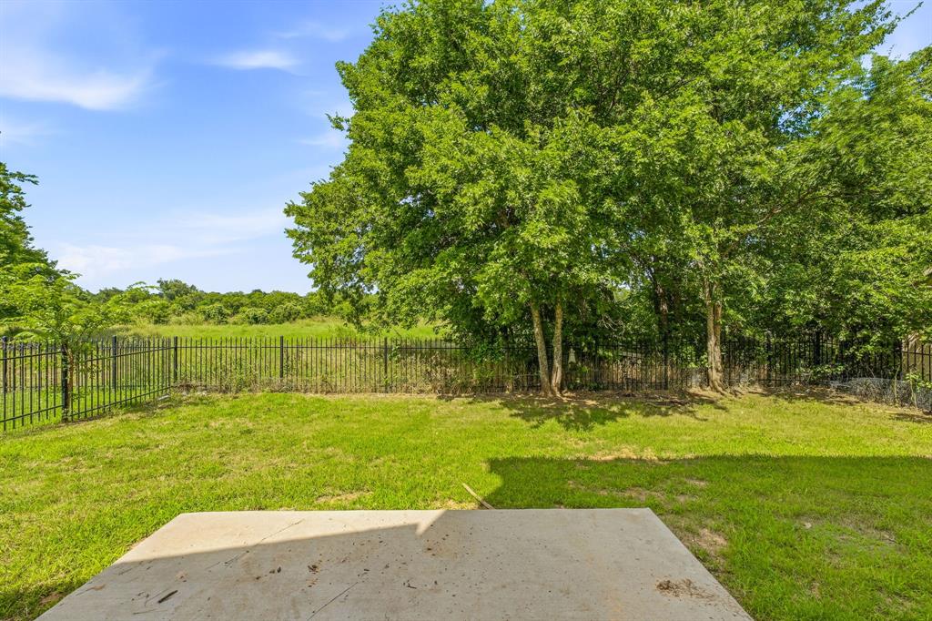 745 North Miller Avenue Stephenville, TX 76401 - Photo 30 of 31 Expansive backyard featuring a concrete patio, a manicured lawn, a black metal fence, and mature trees