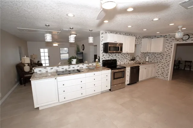 a large kitchen with stainless steel appliances lots of white cabinets