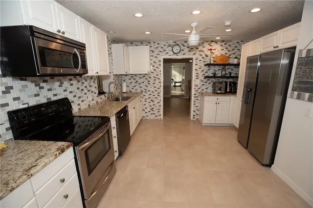 a kitchen with stainless steel appliances granite countertop a refrigerator a stove a sink and a microwave