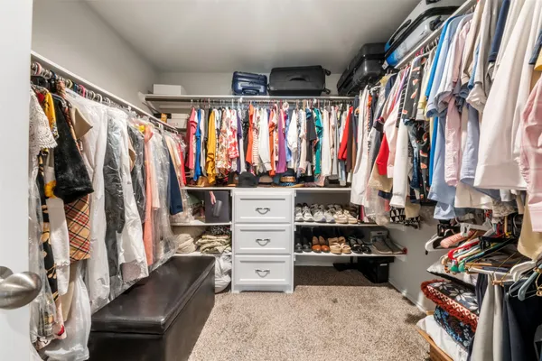 a view of walk in closet with clothes and shoes