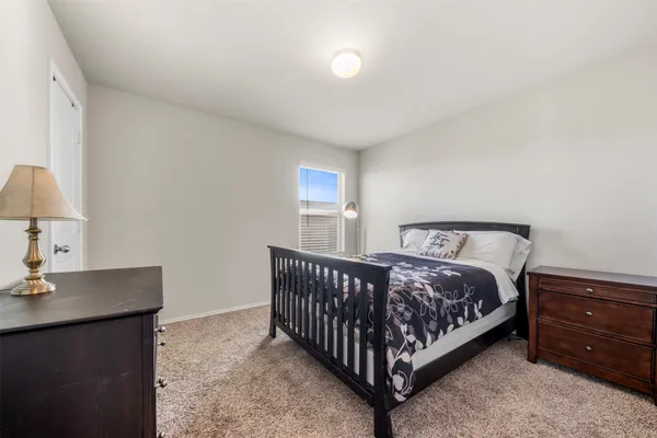 a bed sitting in a bedroom next to a lamp with a dresser and a window