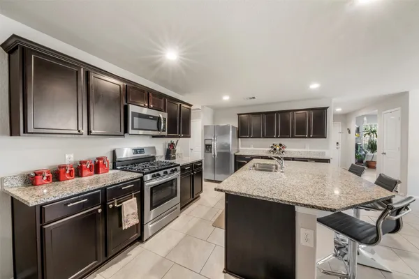 a kitchen with stainless steel appliances granite countertop a sink dishwasher stove top oven and cabinets with wooden floor