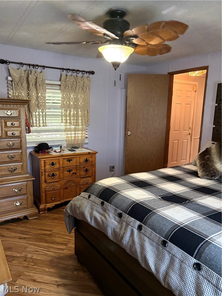 8701 Mayfield Road, Unit 148 Chesterland, OH 44026 - Photo 9 of 24 Bedroom featuring wood-finish flooring, a ceiling fan with light fixture, and a solid wood door