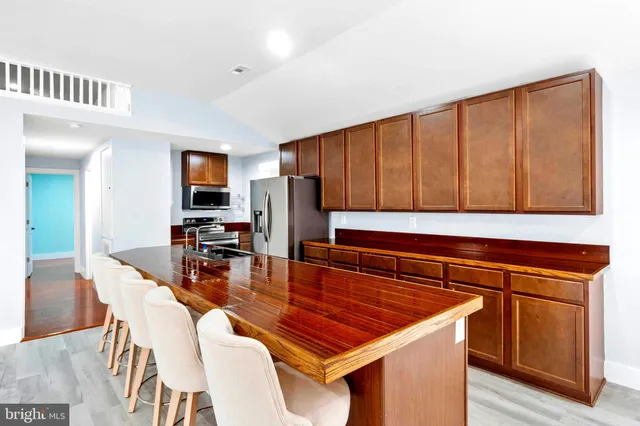 a kitchen with stainless steel appliances granite countertop a refrigerator a stove a sink a dining table and chairs with wooden floor