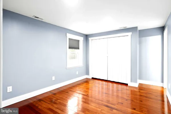 a view of empty room with wooden floor and fan