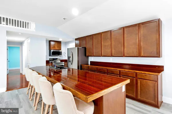 a kitchen with stainless steel appliances granite countertop a refrigerator a stove a sink a dining table and chairs with wooden floor