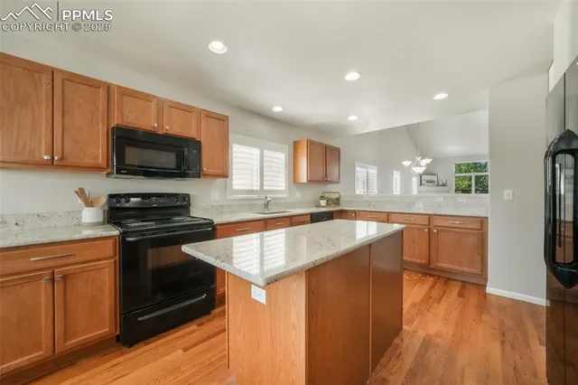 a kitchen with granite countertop a stove top oven a sink dishwasher and a refrigerator with wooden floor