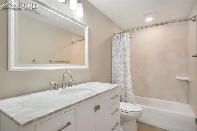 a bathroom with a granite countertop sink a toilet and shower