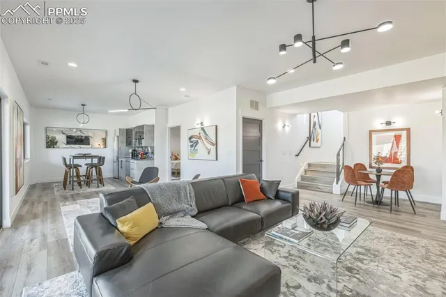 a living room with furniture kitchen view and a wooden floor